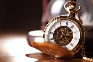 Eine goldene Taschenuhr liegt aufgeklappt auf einem Tisch.
